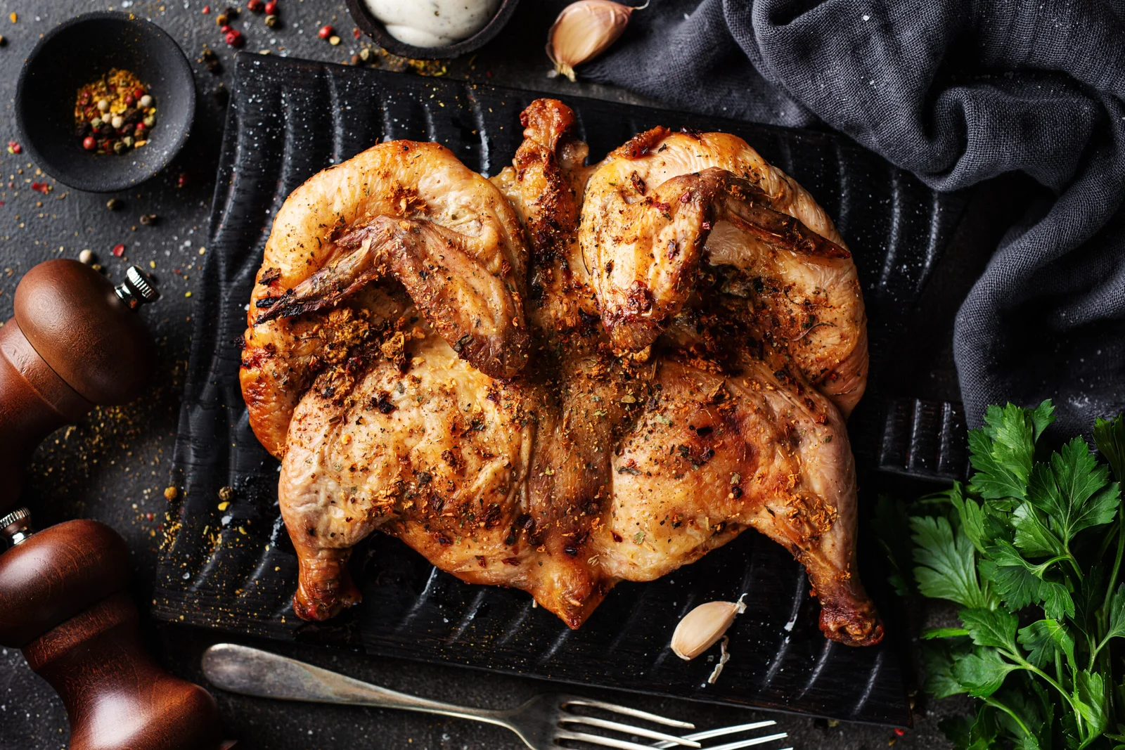 Tasty appetizing baked chicken tabaka with spices served on board. View from above.